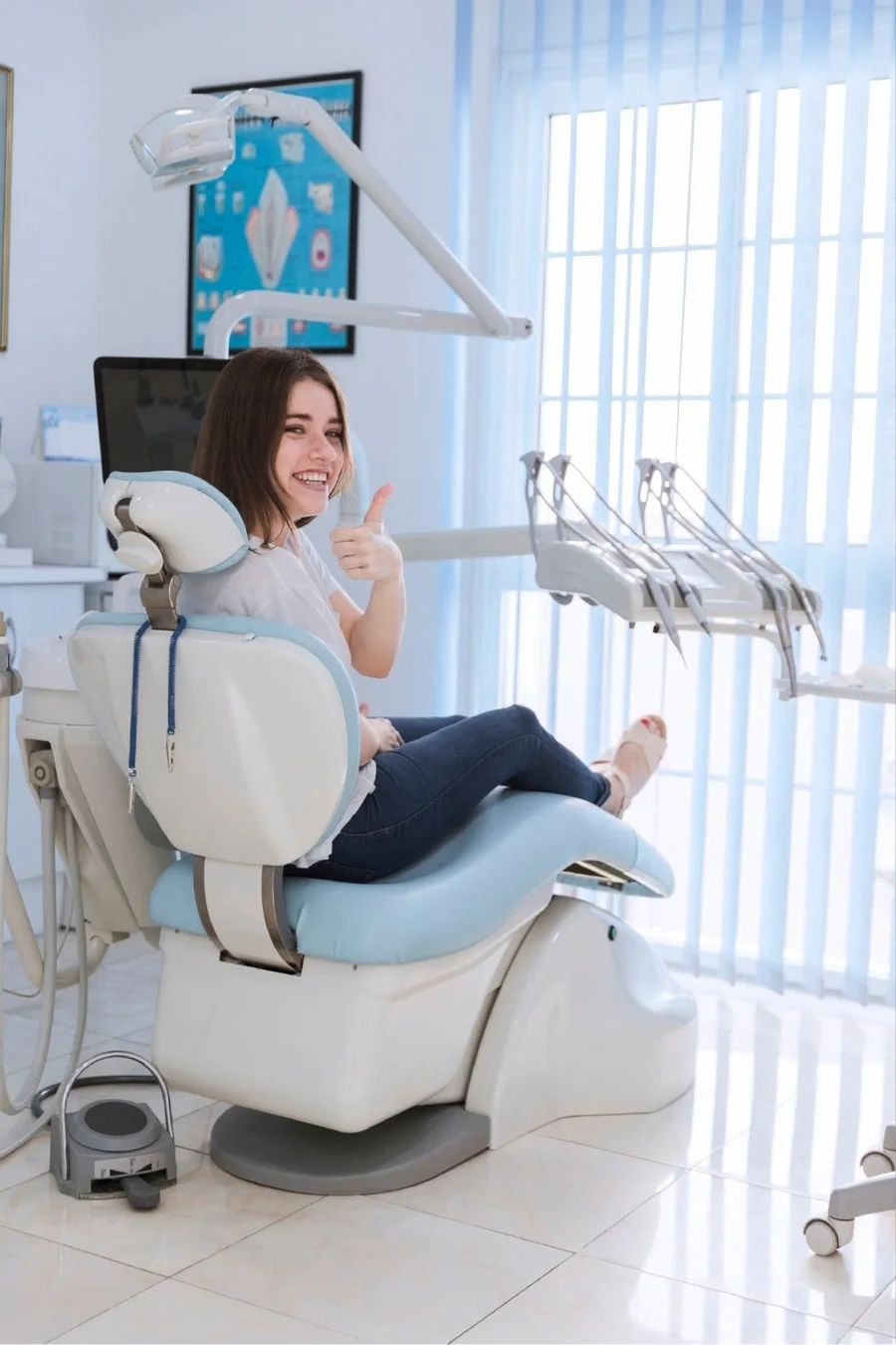 Paciente sorridente fazendo sinal de positivo na cadeira do dentista