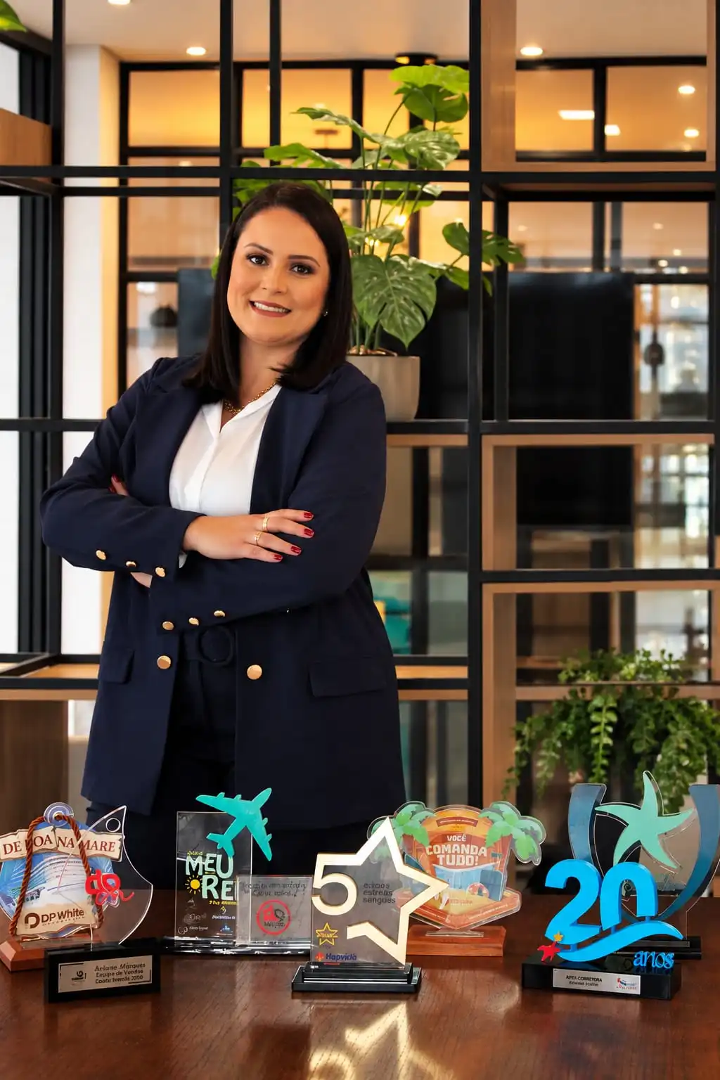 Jennifer Reis, fundadora da Apex Corretora, ao lado dos troféus conquistados pela equipe